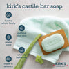 Light green bar of Kirk's Castile soap resting on a wooden soap dish with folded white towel and aloe vera leaf pieces, highlighting gentle scent, soothing aloe vera, and made in America benefits for health and grooming.