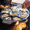 Oval cast iron pan with a dozen oysters grilling on a barbecue, garnished with diced peppers, beside grilled lemon halves, showcasing durable cookware for Kitchen & Food and Grilling collections.