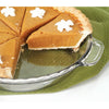 Clear tempered glass pie plate holding a sliced pumpkin pie with dollops of whipped cream on a green textured cloth, suitable for kitchen, cookware, and baking supplies collections