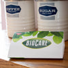Folded BioCare card-style pantry moth trap with green leaf design, placed on wooden surface near vintage-style coffee and sugar canisters, suitable for Home & Decor and Pest Control collections.