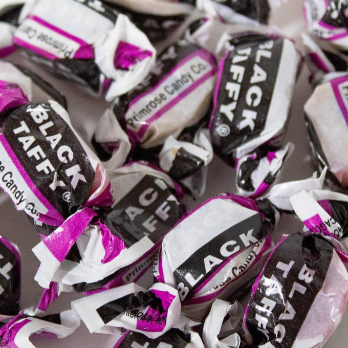 Close-up of individually wrapped black taffy candies with black, white, and purple packaging, highlighting handcrafted nostalgic sweets from Kitchen & Food, Food, Snacks and Sweets, Best Sellers, and Promo Eligible collections.