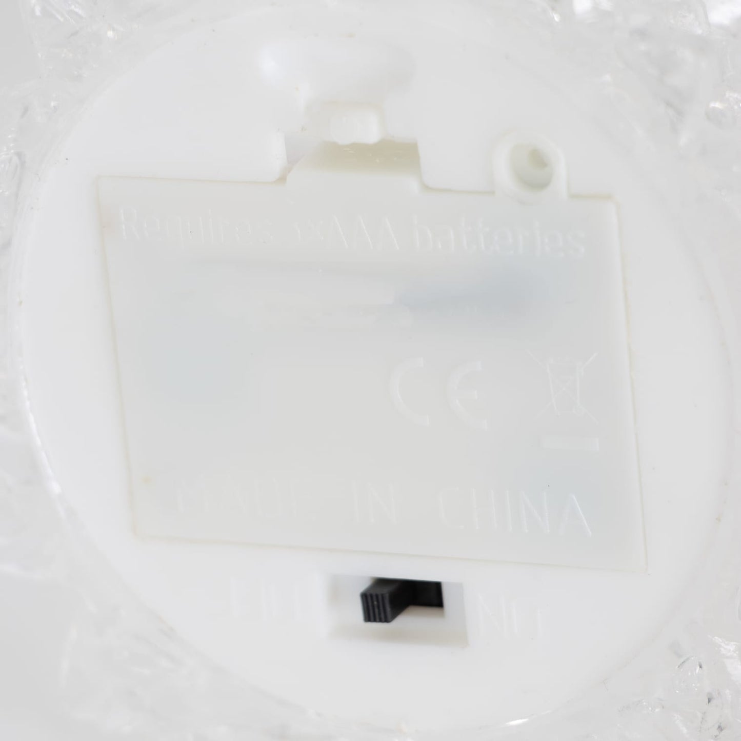 Close-up view of the battery compartment and on/off switch on a clear acrylic Christmas tree base, designed for indoor holiday decor in Home & Decor and Holiday collections.