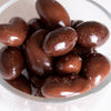 Close-up view of shiny milk chocolate coated nuts in a clear glass bowl, handcrafted in the USA, perfect for Kitchen & Food, Snacks and Sweets, Candy, USA Made, and Best Sellers collections.