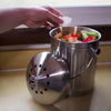 Brushed stainless steel compost pail with perforated lid removed, showing fresh food scraps inside, designed for odor control and countertop use in Kitchen & Food and Composting collections.