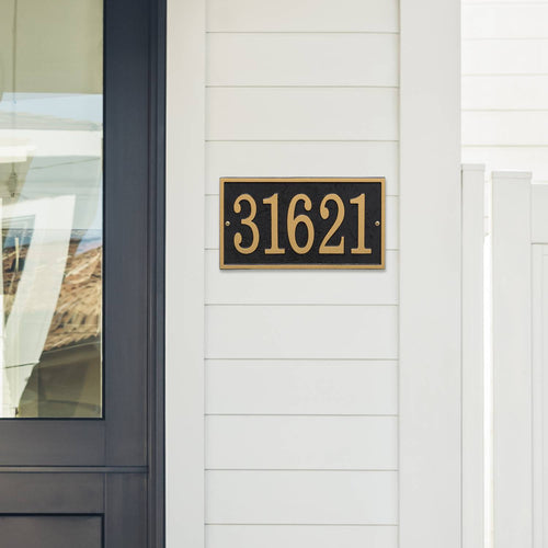 Black and gold rectangular custom address plaque with bold numbers mounted on white siding near a dark door, handcrafted in USA for Home & Decor, Household Helpers, and Mailboxes and Address Signs collections.