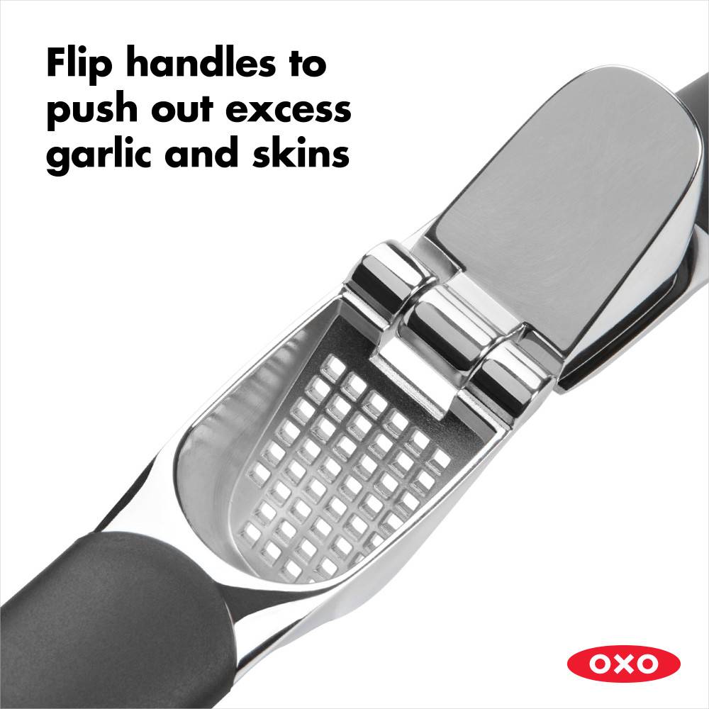 Close-up of a garlic press with large stainless steel chamber and soft black non-slip handles, highlighting the flip mechanism to easily eject garlic and skins, ideal for Kitchen & Food, Kitchen Gadgets, Cooking and Baking Helpers, Best Sellers, and Promo Eligible collections.