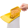 Hand adding loose popcorn kernels into the yellow top of an electric hot air popcorn popper, featured in Kitchen & Food, Popcorn, Kitchen Gadgets, and Best Sellers collections.