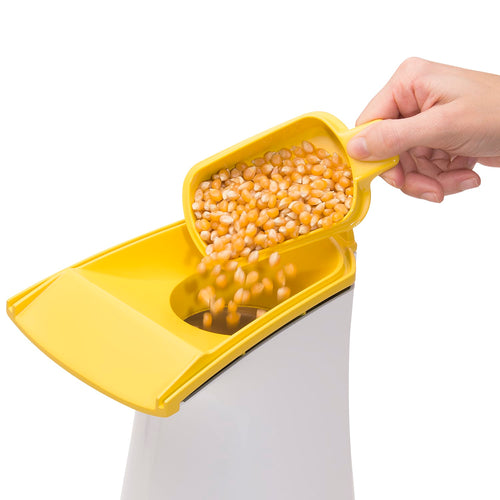 Hand adding loose popcorn kernels into the yellow top of an electric hot air popcorn popper, featured in Kitchen & Food, Popcorn, Kitchen Gadgets, and Best Sellers collections.