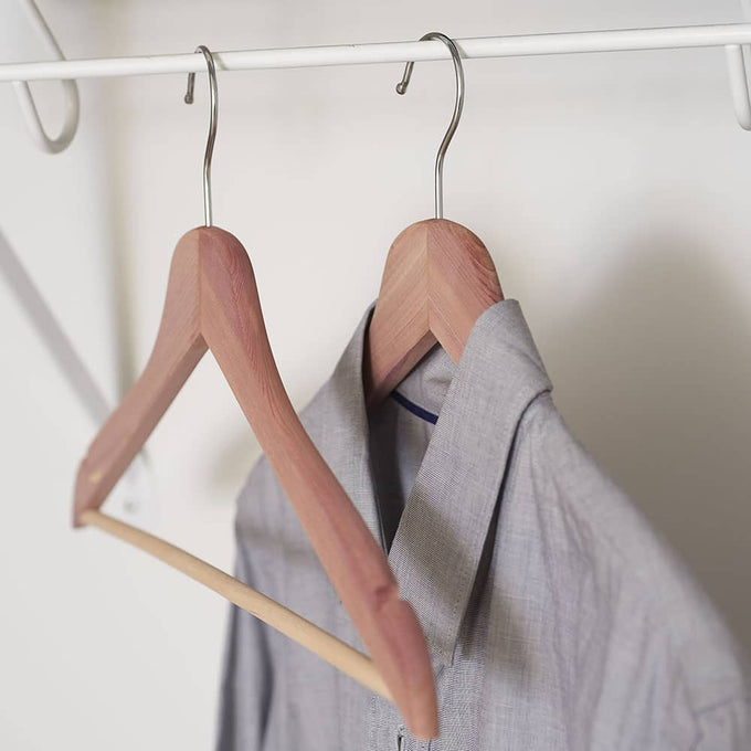 Set of two handcrafted cedar hangers with contoured notched shoulders and fixed horizontal bars, naturally freshening and protecting clothes in Health & Wellness and Home & Decor collections.