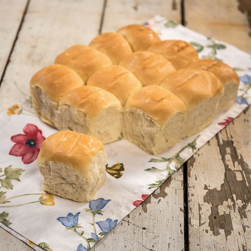 Soft, freshly baked handcrafted dinner rolls arranged on floral cloth atop rustic wooden surface, ideal for Kitchen & Food, Snacks and Sweets, USA Made, Best Sellers, Promo Eligible collections.