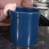 Person lifting a deep blue stoneware crock with a sturdy rim on a kitchen counter, showcasing a handmade USA-made fermenting and food preservation vessel.