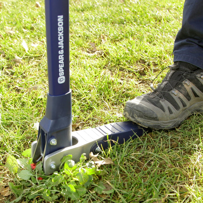 Gardener using a mechanical weed puller with rust-resistant stainless steel claws and long nylon fiberglass handle to remove weeds from green lawn, featured in Farm, Garden & Tool and Lawncare collections.