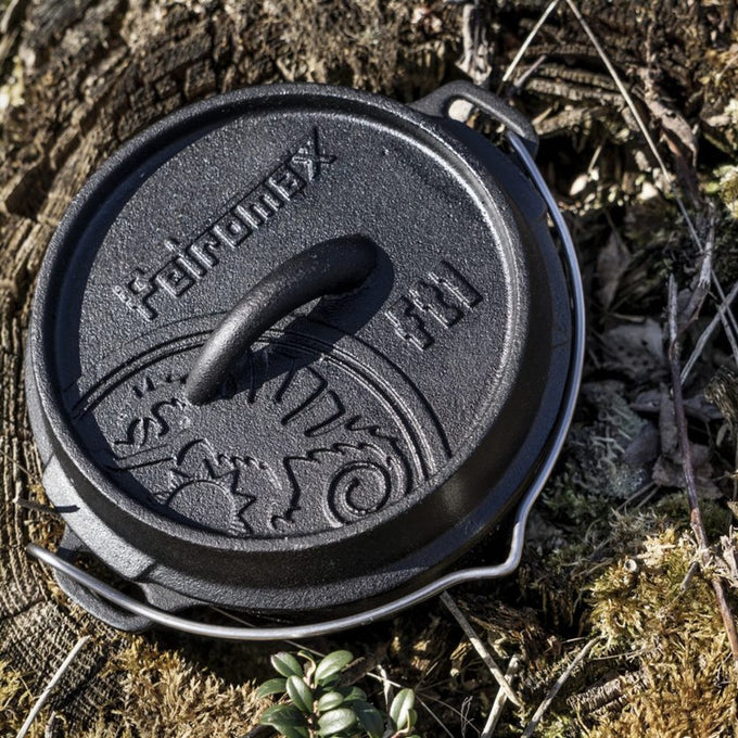 Heavy-duty cast iron Dutch oven with tripod legs and embossed lid featuring a decorative pattern, perfect for outdoor cooking and baking, in Kitchen & Food, Cookware, Cast Iron collections.
