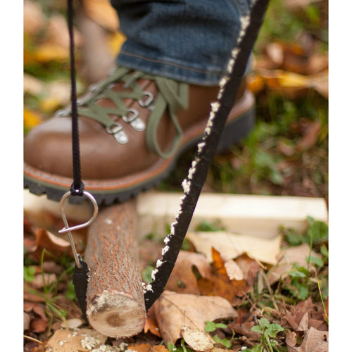 Close-up of a person using a compact handcrafted pocket chain saw to cut a small branch on the ground, showcasing its sharp teeth and sturdy handle, made in USA, ideal for Farm, Garden & Tool and Camping collections.