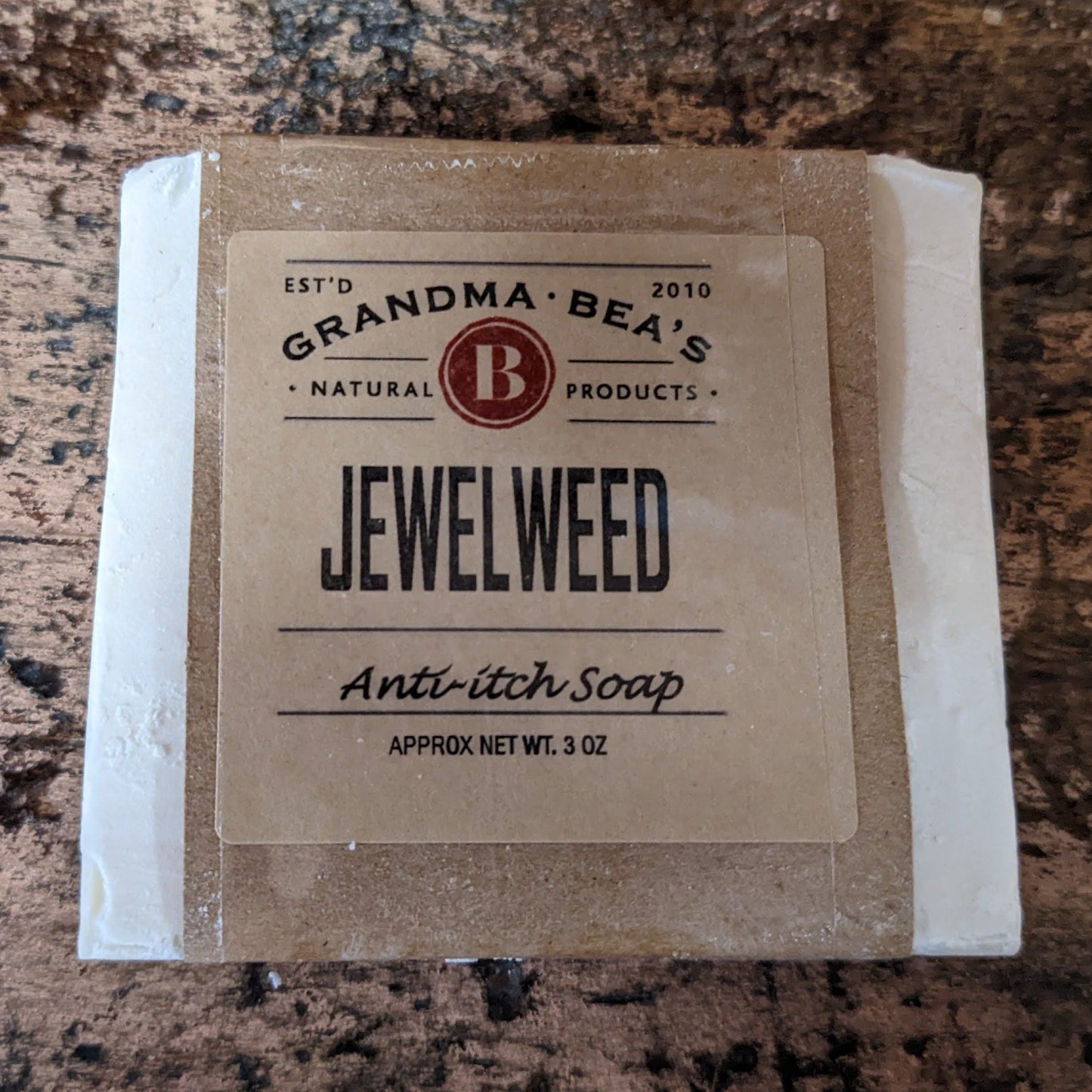Bar of handcrafted jewelweed anti-itch soap wrapped in simple brown paper packaging, featuring natural, USA made wellness product branding for health remedies and soaps collections.