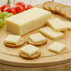 Handcrafted block of shelf-stable cheese with several square slices arranged on round crackers, accompanied by fresh grapes, cherry tomatoes, and oat crackers, perfect for Kitchen & Food, Snacks and Sweets, Pantry, USA Made, and Best Sellers collections.