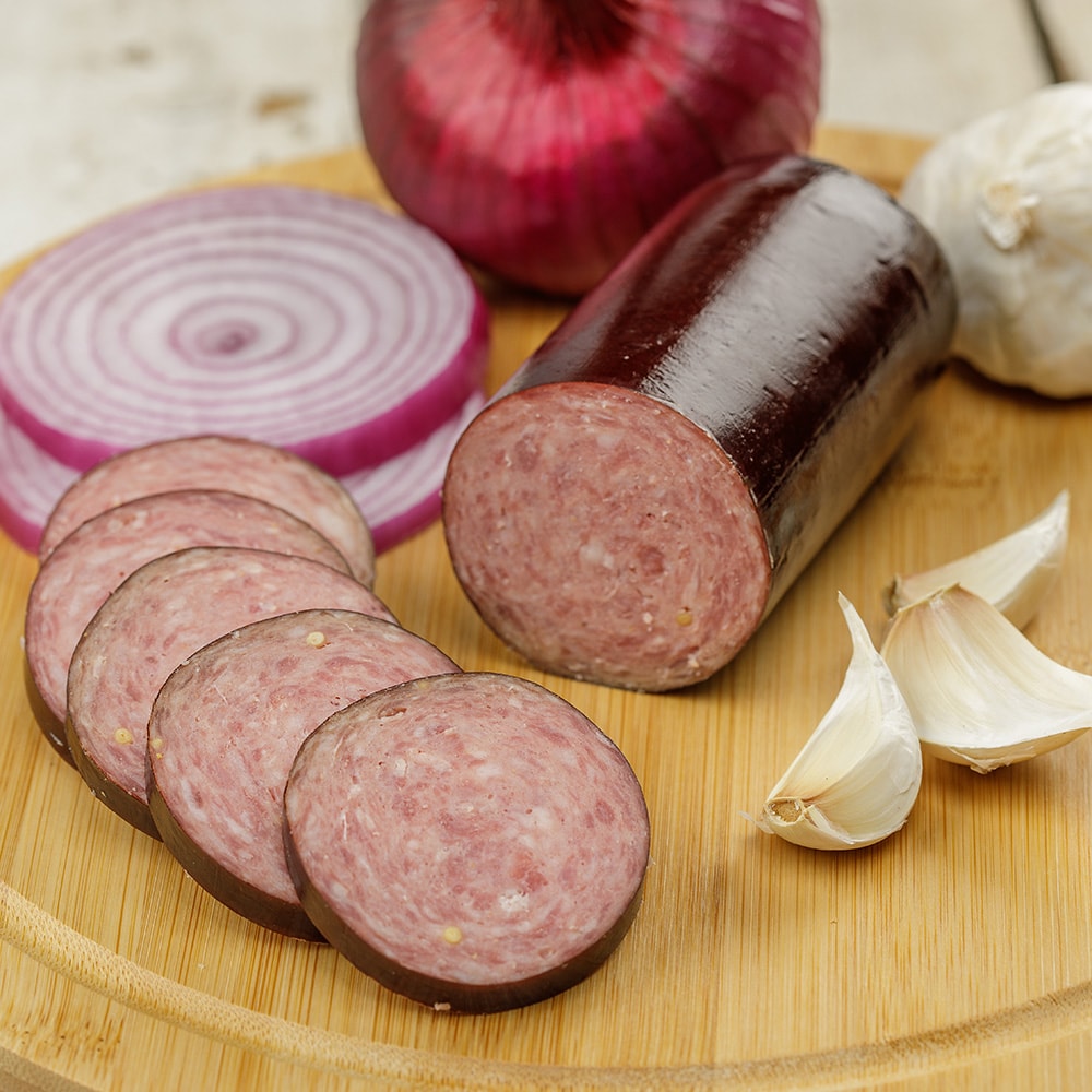 Handcrafted summer sausage from Amish Country, sliced on a wooden board with red onion and garlic cloves, made in USA, ideal for Kitchen & Food, Snacks and Sweets, Pantry, Meats, and Best Sellers collections.