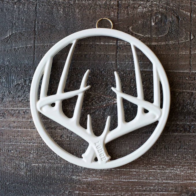 White enamel antler-shaped trivet with built-in hanger and rubber feet, designed to protect surfaces, stylish addition for Kitchen & Food, Dinnerware, Storage and Serving, Best Sellers, and Promo Eligible collections.
