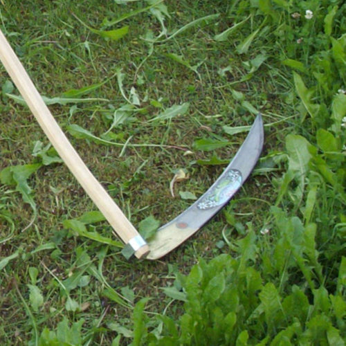 Handcrafted farming scythe with decorated curved metal blade and smooth wooden handle resting on green grass, suitable for efficient mowing in Farm, Garden & Tool, Lawncare, Best Sellers, Promo Eligible collections.