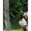 Handcrafted 28-inch pocket saw with heat-treated steel teeth and ergonomic black handles cutting a small tree branch, ideal for farm, garden, wood cutting, and USA Made collections.