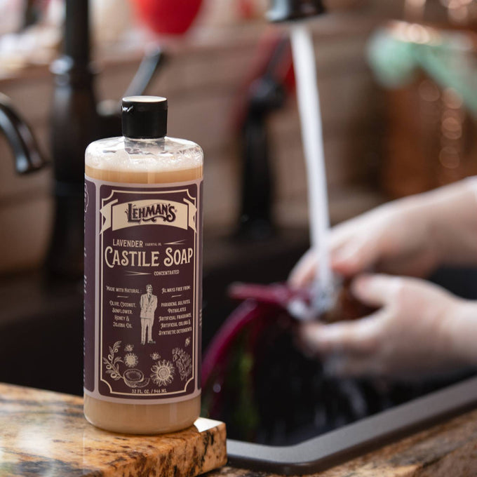 Amber bottle of handcrafted Lehman's castile liquid soap with lavender scent placed on kitchen counter near running water, highlighting USA made natural soap in health and grooming collections.
