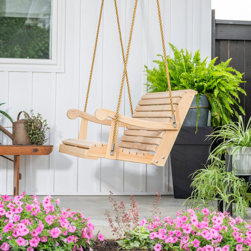 Handcrafted cypress porch swing with smooth wooden slats and sturdy rope suspension, set on a porch surrounded by vibrant pink flowers and lush green plants in outdoor home decor collections.