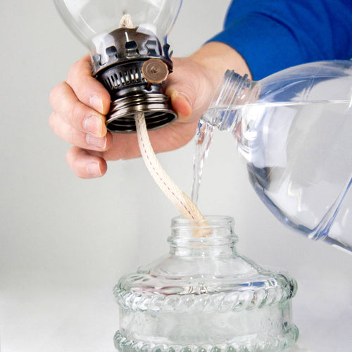 Handcrafted oil lamp with fabric wick being filled through clear glass base, suitable for Lamps & Lighting, Oil Lamps, Wall Lamps, Best Sellers, and Promo Eligible collections.