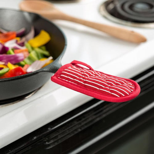 Red and white striped padded hot handle cover fitted over a cast iron skillet handle on a white stovetop with sautéed vegetables, ideal for Kitchen & Food, Cookware, Cast Iron, Best Sellers, and Promo Eligible collections.
