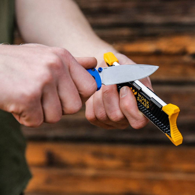 Hands sharpening a fixed-blade knife with a compact Work Sharp Pocket Knife Sharpener featuring yellow guides, ideal for Farm, Garden & Tool, Knives & Axes, and Sharpening collections.