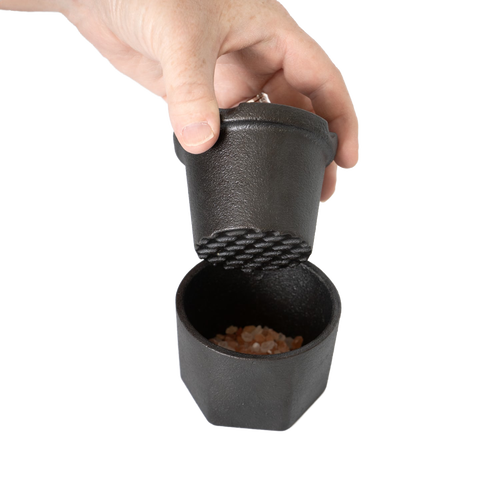 Handheld cast iron spice grinder set with textured grinding surface and bamboo lid, designed to crush coarse pink Himalayan salt crystals, part of Kitchen & Food and Best Sellers collections.
