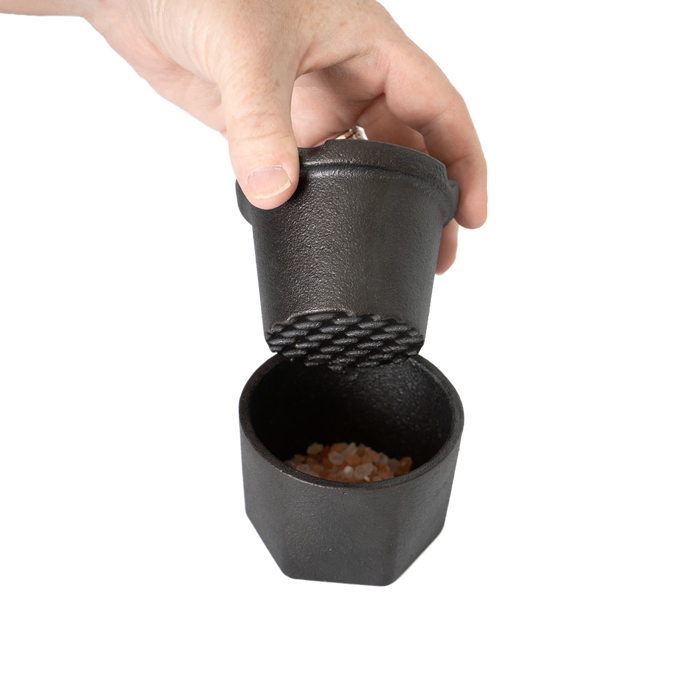 Handheld cast iron spice grinder set with textured grinding surface and bamboo lid, designed to crush coarse pink Himalayan salt crystals, part of Kitchen & Food and Best Sellers collections.