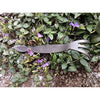 Handcrafted all-steel cultivator with a three-pronged fork and cobra-shaped head resting on green foliage with purple flowers, ideal for Farm, Garden & Tool and Digging and Cultivating collections.