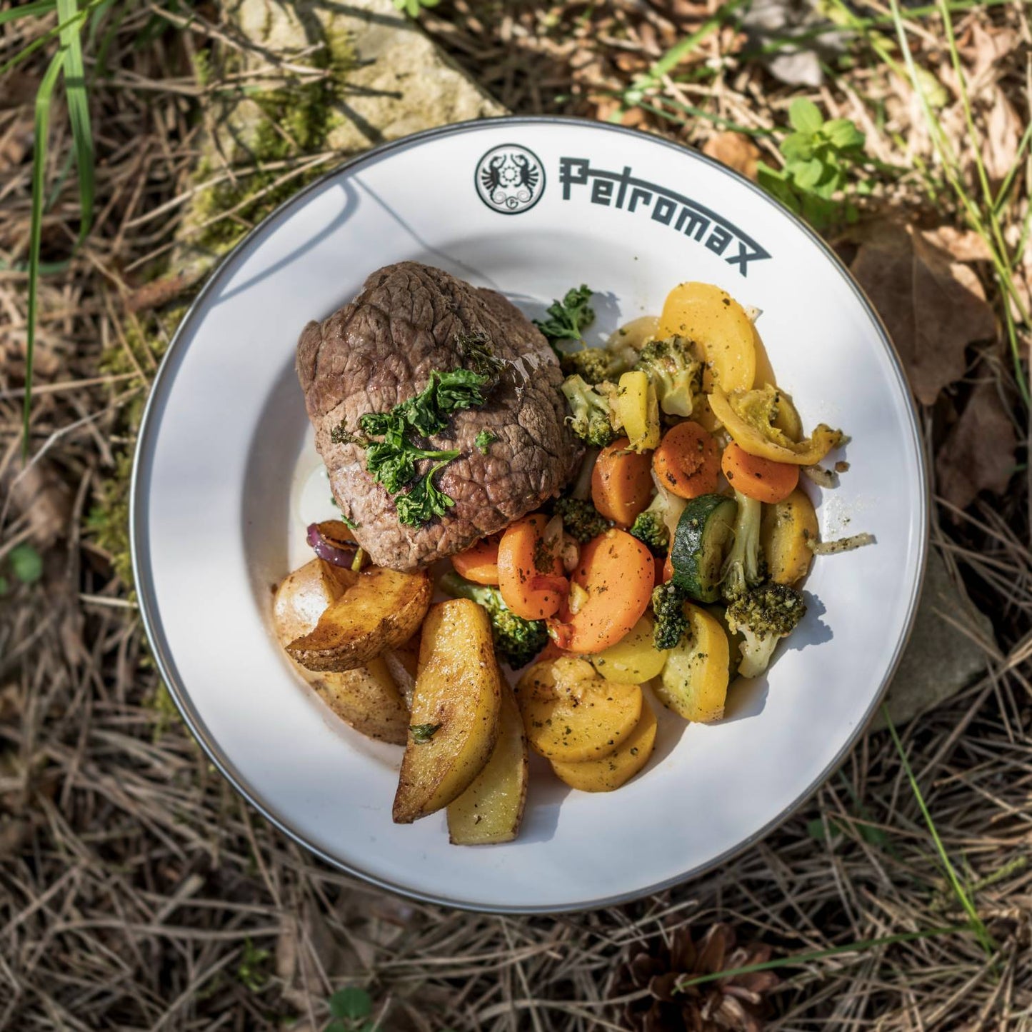 Sturdy white enamel plate with black rim and Petromax logo, holding grilled steak and seasoned mixed vegetables, perfect for camping, kitchen, and outdoor dining in Farm, Garden & Tool, Dinnerware, Best Sellers, and Promo Eligible collections.