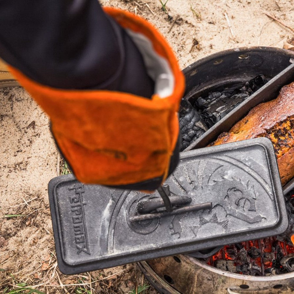 Gloved hand using a curved metal lifter to safely remove a hot cast iron Dutch oven lid over an outdoor campfire, featured in Farm, Garden & Tool, Camping, Best Sellers, and Promo Eligible collections.