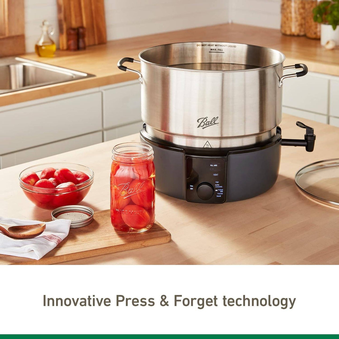 Electric water bath canner with stainless steel pot and black base featuring heat sensors and control dial, shown with fresh tomatoes in jar and kitchen countertop setup for food preservation.
