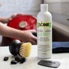 Bottle of biodegradable cleaner for enameled cast iron and ceramic stoneware with a stiff-bristle brush, pan scraper, and black clips on a kitchen counter, part of Kitchen & Food and Cookware collections.