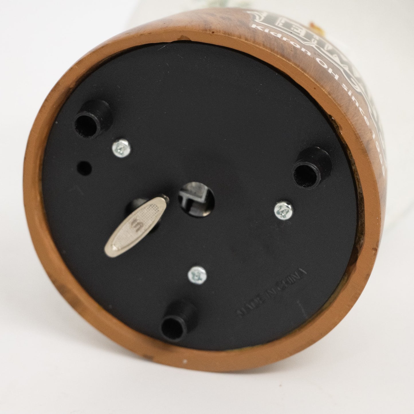 Bottom view of handcrafted musical snow globe base showing winding key, black plastic with three support feet, part of holiday decor and best sellers collections.