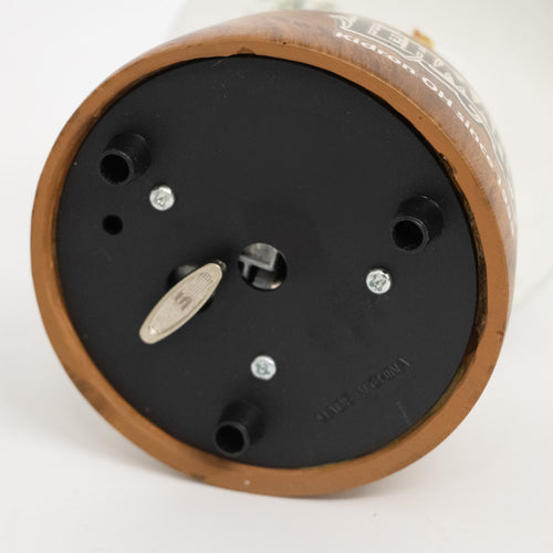 Bottom view of handcrafted musical snow globe base showing winding key, black plastic with three support feet, part of holiday decor and best sellers collections.