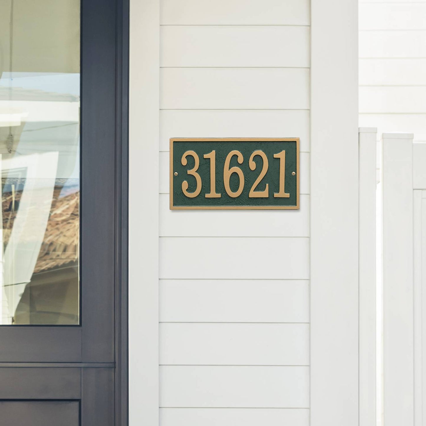 Green and gold custom address plaque mounted on white siding near a modern black door, handcrafted in the USA, featured in Home & Decor, Mailboxes and Address Signs, and Best Sellers collections.