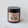 Dark amber glass jar with a black lid containing natural foot soak blend, labeled Grandma Bea’s, made in USA, ideal for soothing and refreshing tired feet in Health & Wellness collections