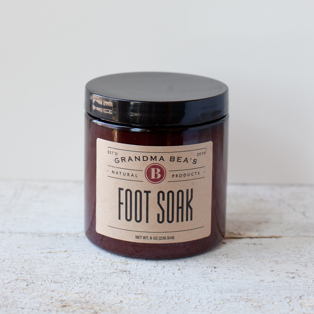 Dark amber glass jar with a black lid containing natural foot soak blend, labeled Grandma Bea’s, made in USA, ideal for soothing and refreshing tired feet in Health & Wellness collections