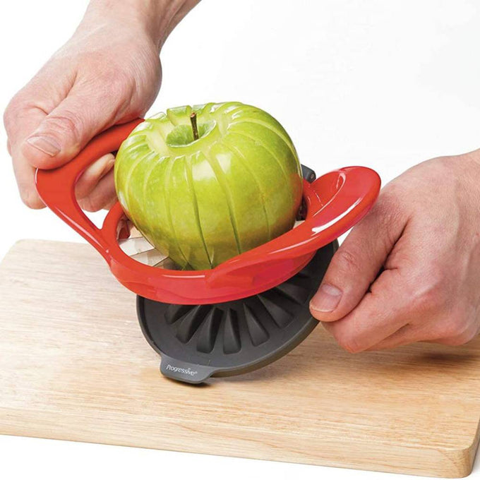 Handheld thin apple slicer with a red hard plastic handle and stainless steel blades cutting a green apple into uniform wedges, ideal for kitchen and cooking helpers collections.