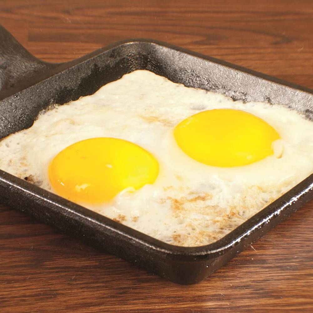 Handcrafted 5-inch square cast iron skillet made in USA, shown cooking two sunny-side-up eggs, perfect for small meals in Kitchen & Food, Camping, and Cast Iron collections.