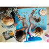 Three people working together on a uniquely shaped 100-piece sloth puzzle with large pieces on a blue table, alongside a book and a bowl of popcorn, ideal for children’s toys and games collections.