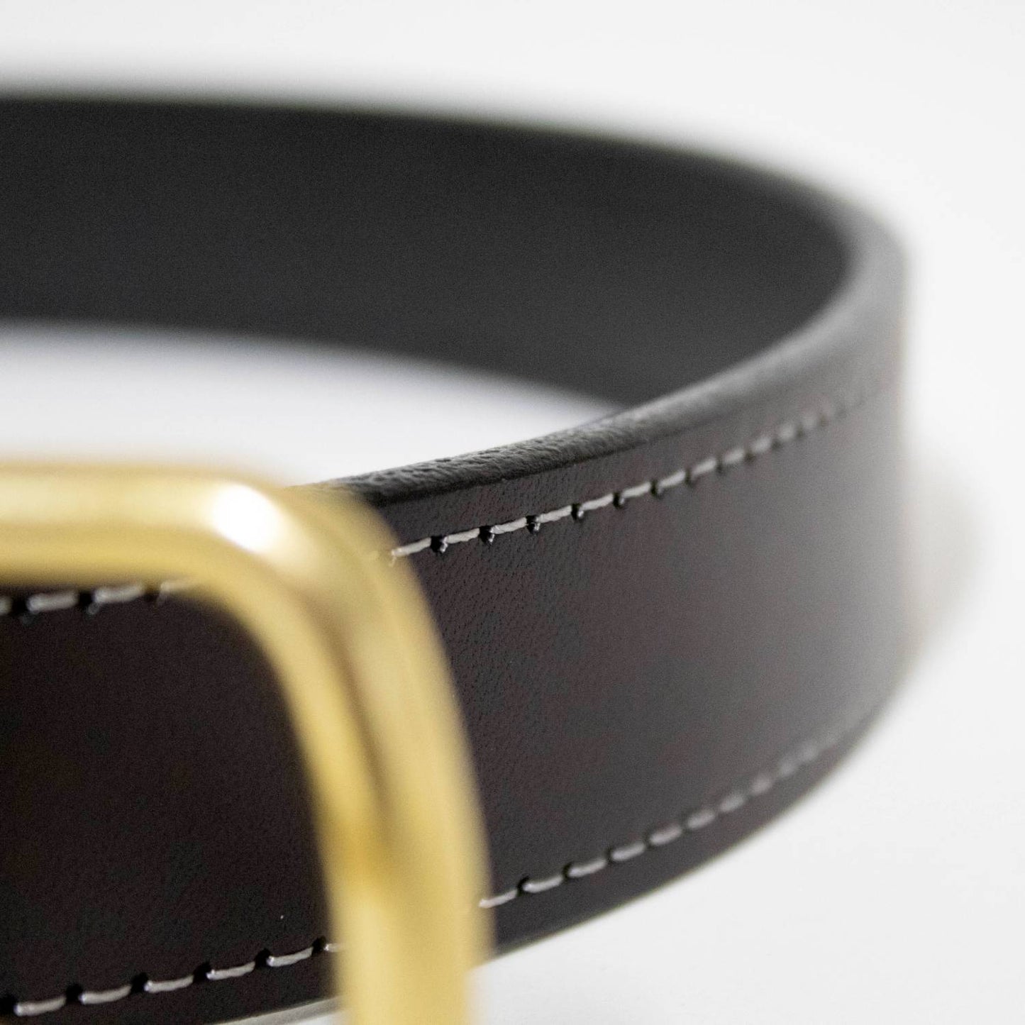 Close-up of a handcrafted brown leather belt with fine contrasting stitching and polished brass buckle, Amish made in USA, featured in Clothing and Accessories and Best Sellers collections.