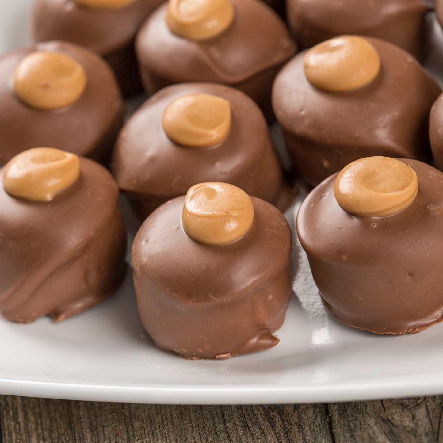 Close-up of smooth milk chocolate-covered peanut butter confections with creamy peanut butter dollops on top, handcrafted in Ohio's Amish Country, featured in Kitchen & Food and USA Made collections.