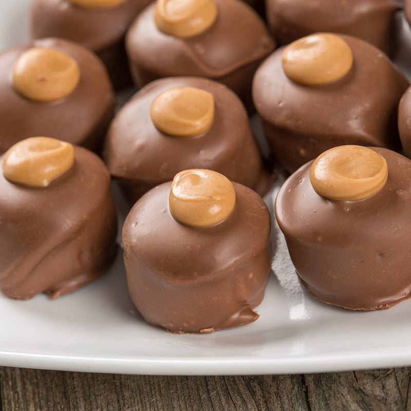 Close-up of smooth milk chocolate-covered peanut butter confections with creamy peanut butter dollops on top, handcrafted in Ohio's Amish Country, featured in Kitchen & Food and USA Made collections.