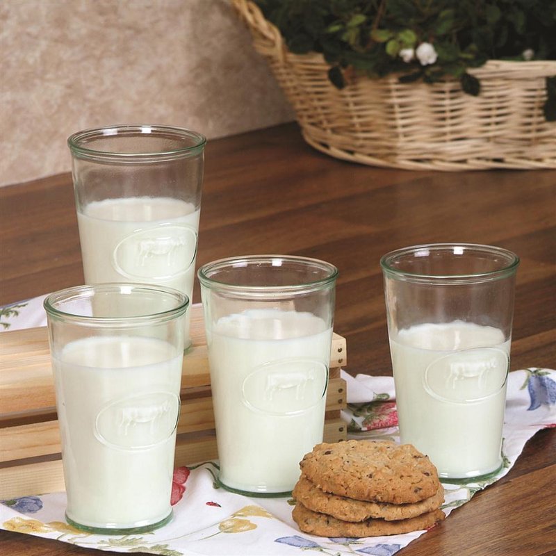 Set of four light green recycled glass tumblers embossed with a cow design, filled with milk on a wooden table with cookies, featured in Kitchen & Food and Dinnerware collections.