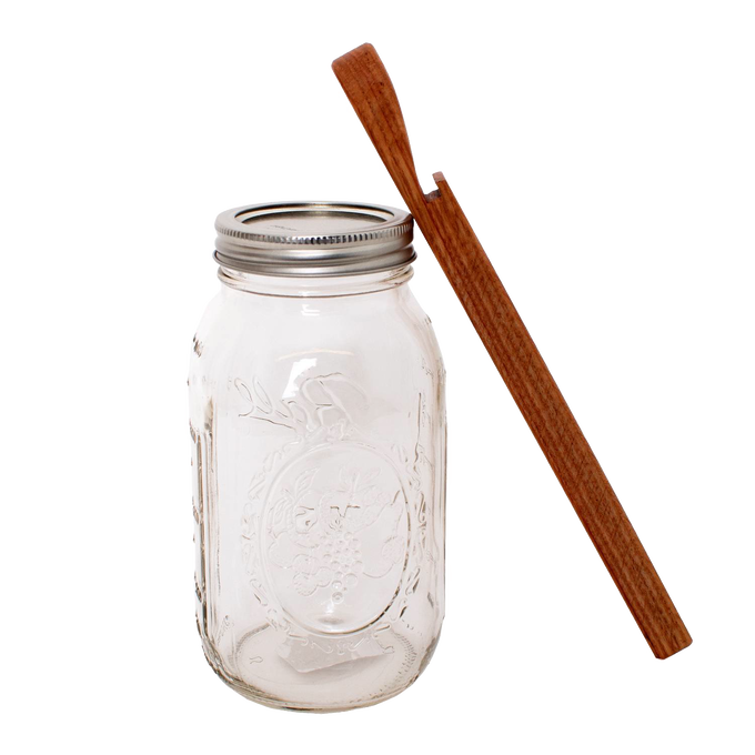 Handcrafted oak jar opener beside a clear mason jar with metal lid, designed for easy seal removal without damaging lids, featured in Kitchen & Food and Canning Accessories collections.
