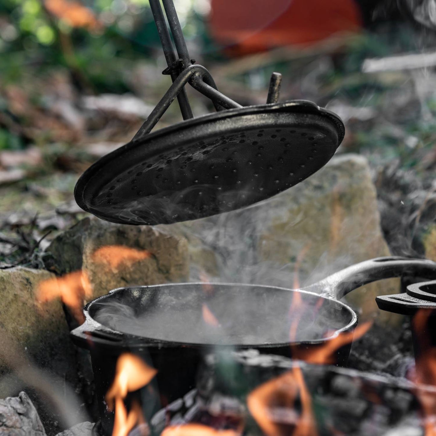 Handcrafted cast iron saucepan with lid steaming over an open fire, designed for camping, farm, garden, cookware, kitchen, cast iron, pots and pans, and best sellers collections.